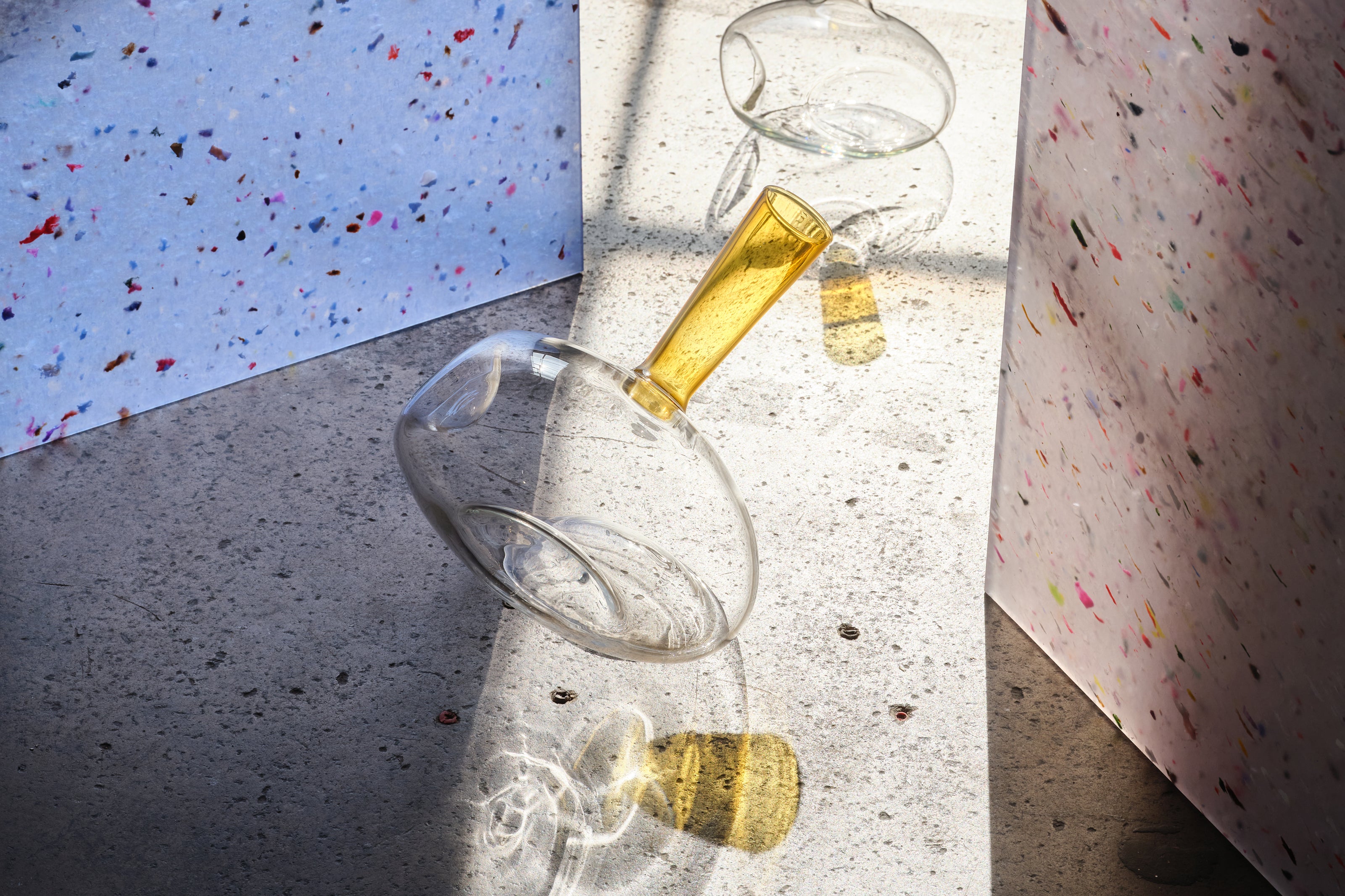 Wine decanter with yellow neck on a concrete surface.