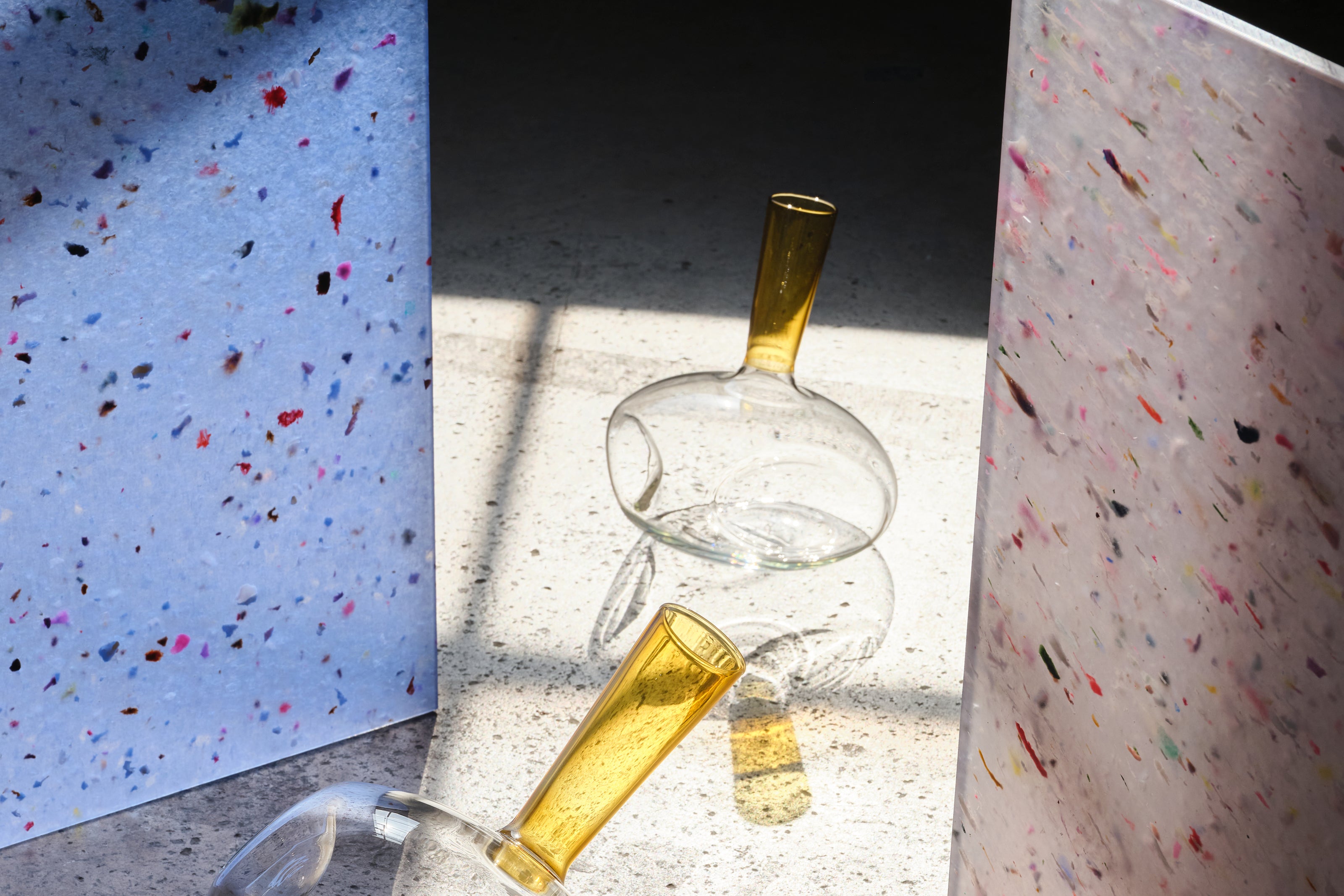 Glass decanter with yellow accent on a concrete surface.