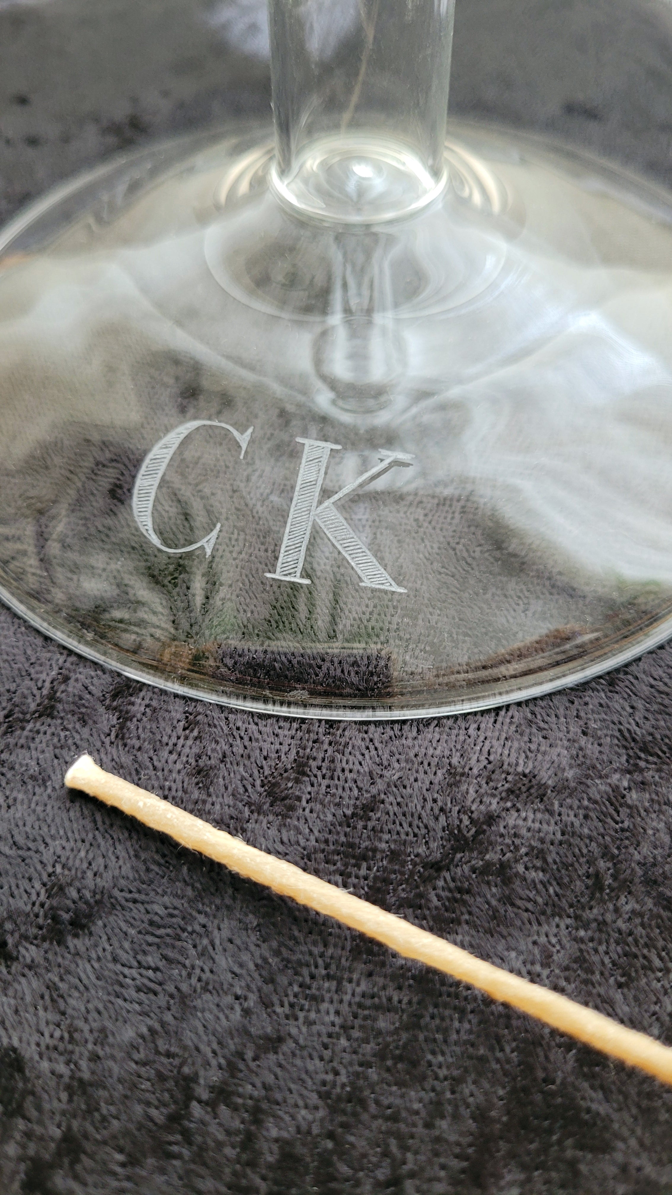 Close-up of a glass candleholder with 'CK' engraved onto the base